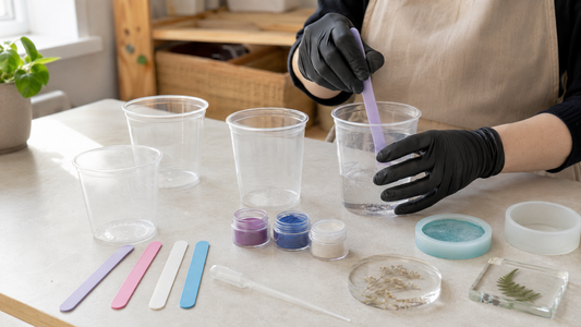 Resin maker mixing clear resin in a tidy daylight workspace with cups, moulds and teal tools
