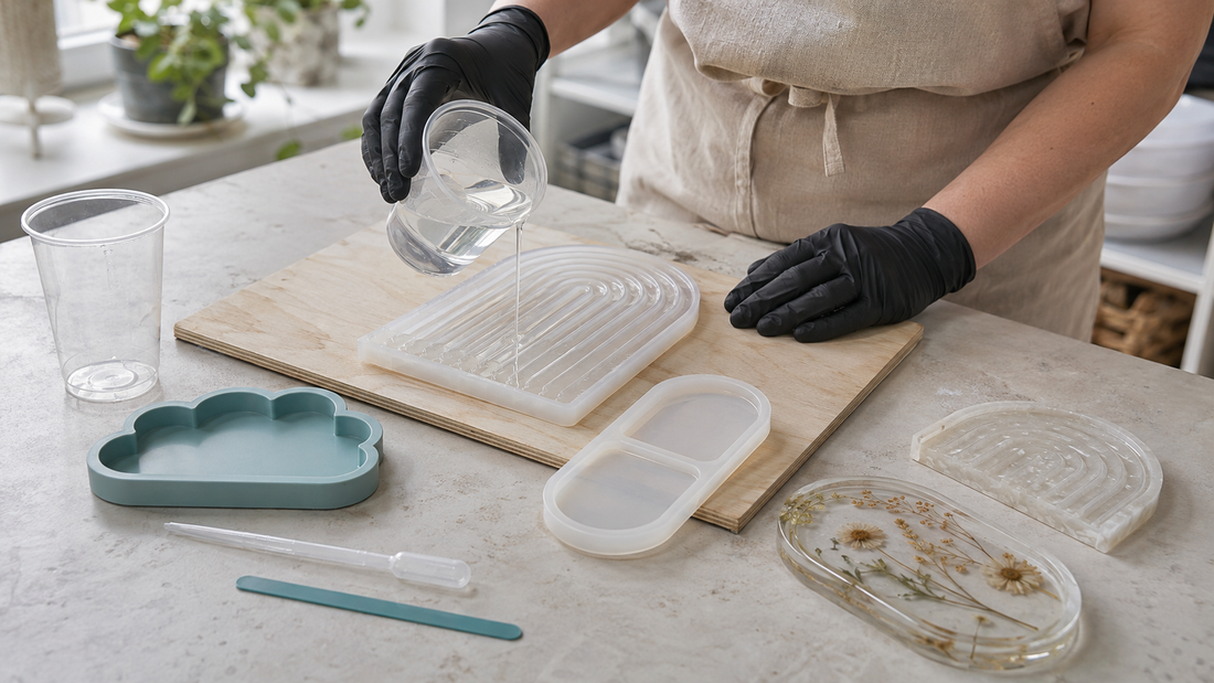 Gloved maker pouring clear resin into a level silicone tray mould on a tidy daylight workbench