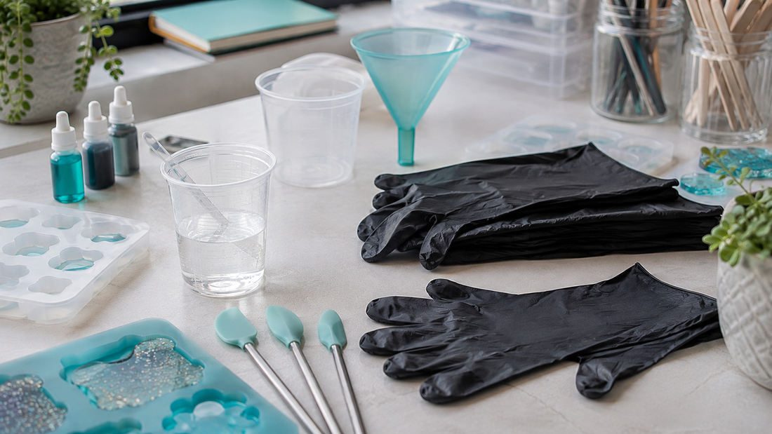 Box of nitrile gloves beside mixing cups, resin tools and moulds on a clean, organised craft workspace