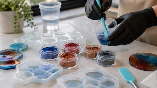 Mica powders in blue, red and copper shades beside clear resin and mixing tools on a tidy resin crafting workspace